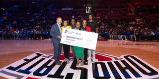 six people stand on a basketball court holding a large check presented to nicole holt as the 2024 ohio education association aspiring educator at central state university