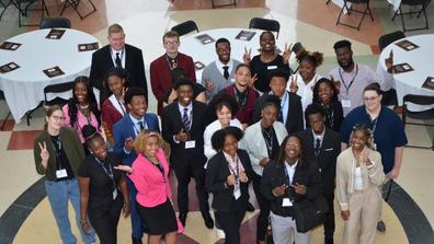 central state university scholars stand in a group while looking at a camera taking a photo from above