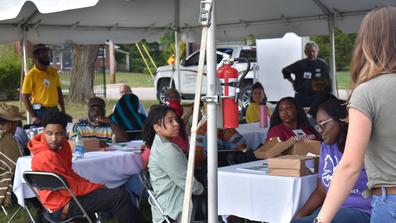 a large group of people sits under a tent at the 2023 land-grant open house at central state university