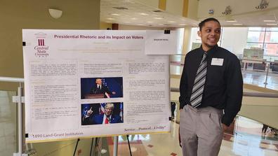 daquan neal stands beside his research poster on presidential rhetoric and its impact on voters