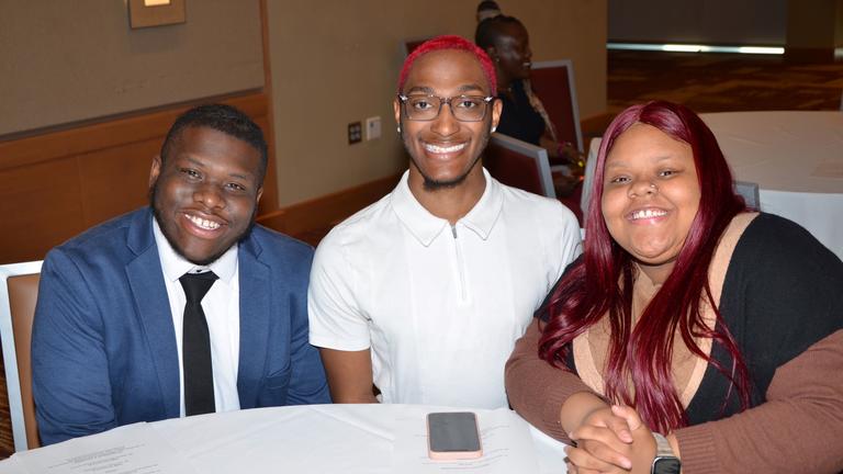 three central state university students around a table with a white tablecloth