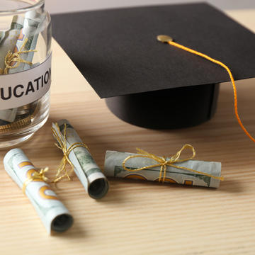Jar of money beside a graduation cap