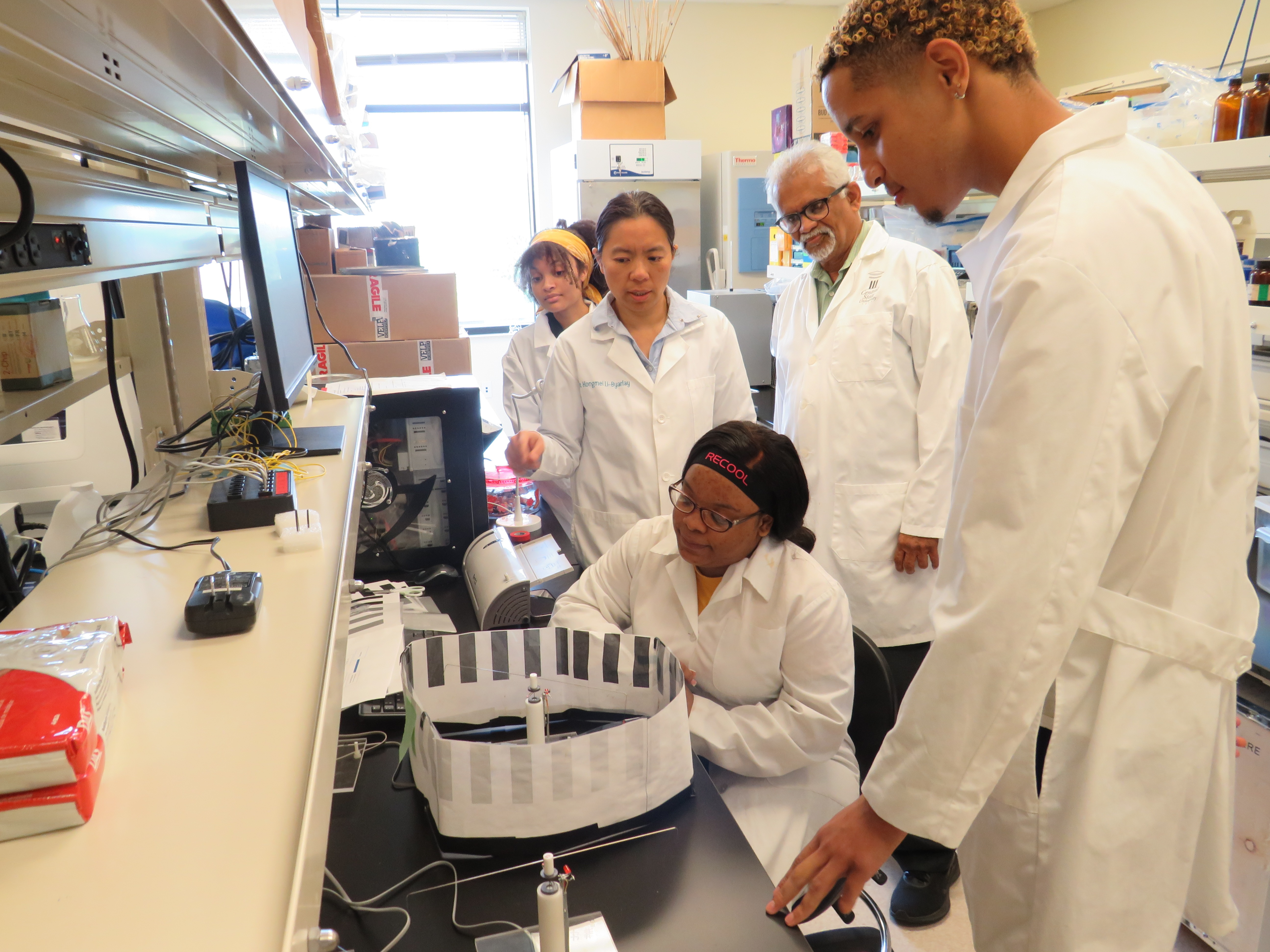 CSU Research Assistant Professor of Entomology Dr. Hongmei Li-Byarlay, works with students in a bee lab while Sharath Krishna, Ph.D., CSU professor of biology and agricultural and life sciences, looks on.