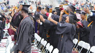 graduates adjust the tassels on their caps