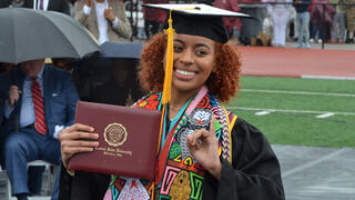 a student proudly displays her diploma