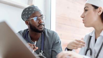 A Black healthcare worker collaborates with a colleague.