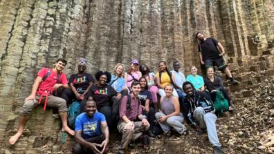 A group of young adults sits in front of sediment in Machame Kaskazini