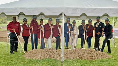 A group of people stands under a tent with a pile of dirt in front of them. They are holding shovels in preparation to break ground on a new research facility at Central State University.
