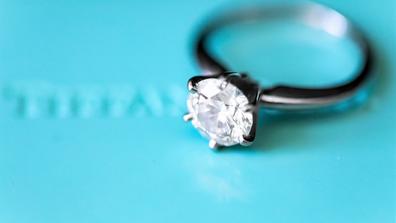 closeup of a diamond ring laying on a light blue background