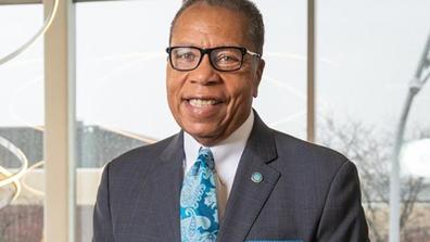 A man wearing a black suite jacket and blue tie