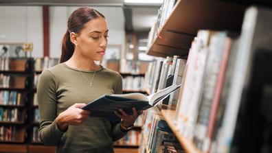 college student with book in library