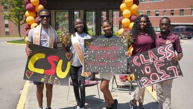 five Central State University students hold signs welcoming the class of 2027 to campus