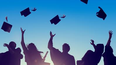 Silhouettes of graduates throwing caps