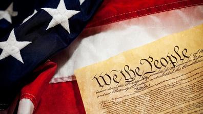 A closeup of the U.S. Constitution and flag