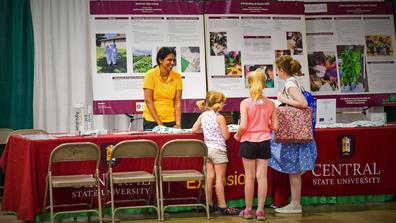 A representative of Central State University Land-Grant talks with youth at the 168th Ohio State Fair