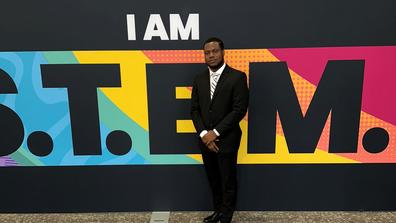 Central State University student Phanuel Cofie of Ghana stands in front of a colorful sign that says "I am S.T.E.M."
