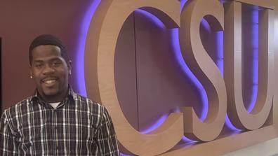 JC Jamason, building manager of the Central State University Student Center, beside a CSU sign
