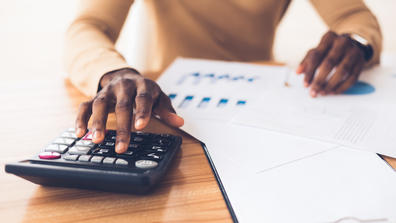 hands of an African American accountant working with a calculator and accounting materials