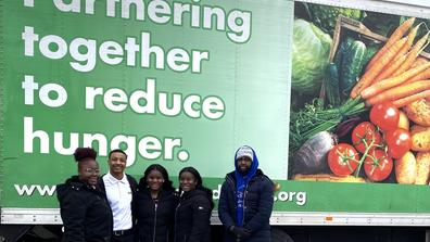 five Central State University students in front of a large semi with the words partnering together to reduce hunger