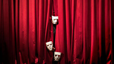 theater masks hanging from a curtain on a stage