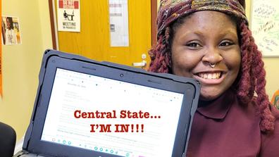 a young african american person with braids and a nose ring holds a laptop with the words central state... I'm in celebrating her acceptance to central state university