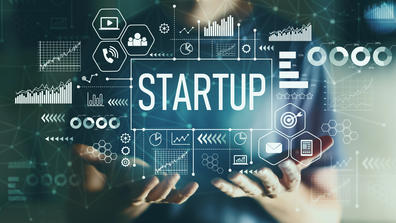 a person holds the word startup in a tech screen