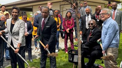 four people hold shovels before planting a tree at central state university in celebration of the ohio department of natural resources 75th anniversary