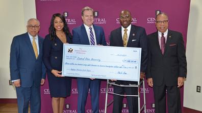 five people holding a large ceremonial check