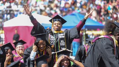 central state university graduate raises arms in celebration