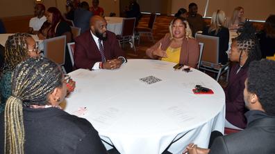 six people sit at a round table in a lively discussion at central state university