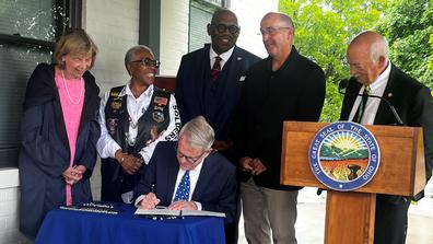 ohio governor mike dewine signs a bill while five others look on