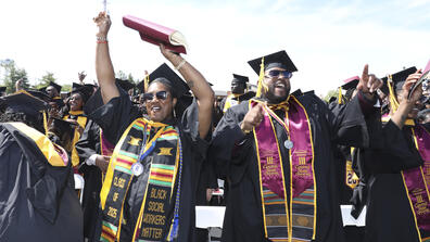class of 2025 graduates celebrate with their hands in the air during commencement
