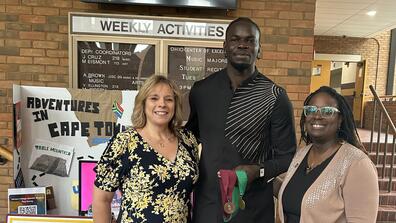 doctors theresa aikens and sarah armstrong-jones stand next to ibrahima jarjou holding honors medallions
