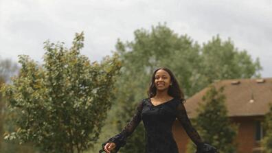 a young black woman with long brown hair wearing a black dress