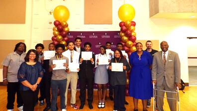a large group of young adults standing with certifications for completion of the first honda american engeering academy at central state university