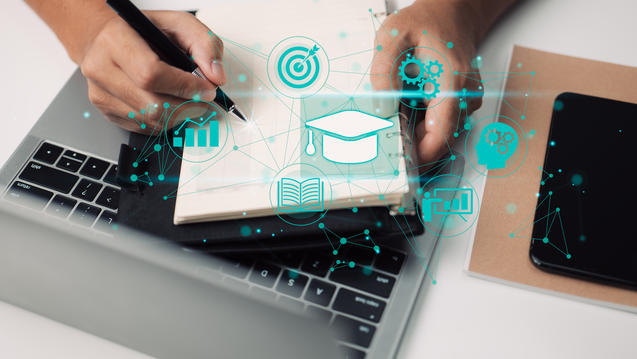 Hands holding a notebook over a open laptop