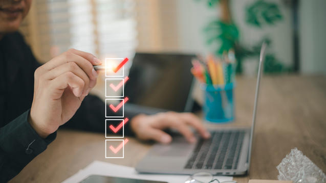 Person sitting in front of open laptop checking off a checklist