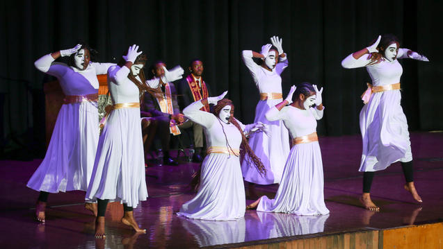 Central State University students perform on a stage in white gowns and gloves