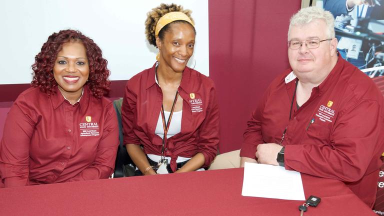 Three people wearing Central State University maroon and gold smile at the camera.