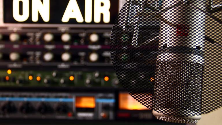A closeup of a microphone in a radio station with the words "On Air" in all caps