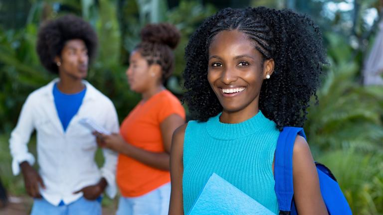 African American woman holding folder with backpack and two other Black students in the background