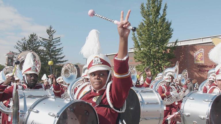 A drummer with the Invincible Marching Marauders at Central State University gives a peace sign to a crowd gathered for a Homecoming performance