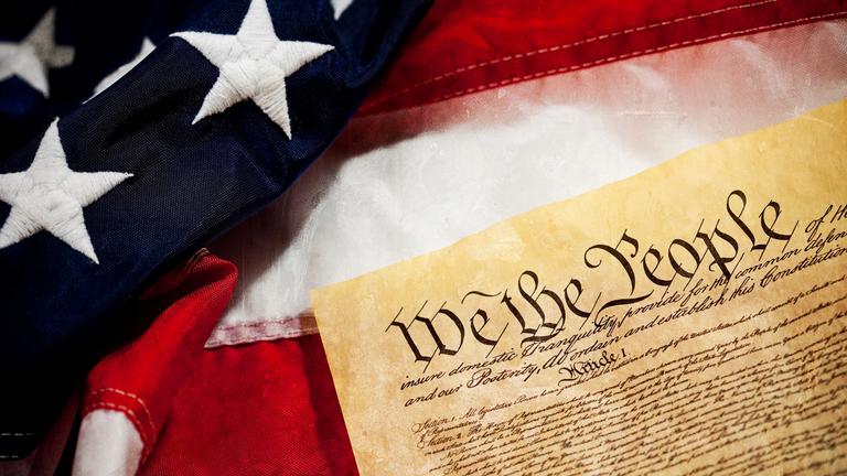 A closeup of the U.S. Constitution and flag