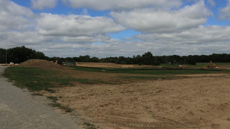 An open field prepared for construction with a partly cloudy sky