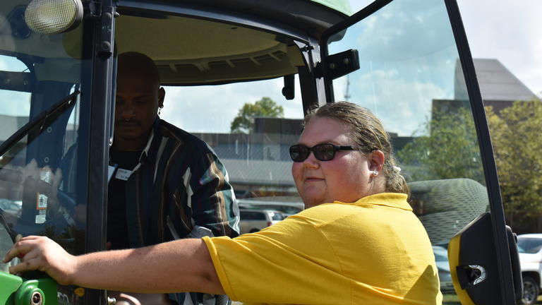 a person wearing a yellow shirt talks to a man in a tractor at the 2023 Black Farming Conference at Central State University