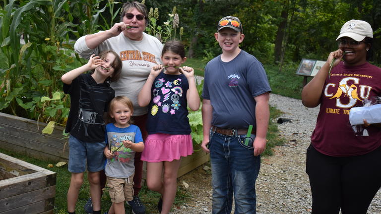 a group of adults and youth simultaneously take a bite of a green bean