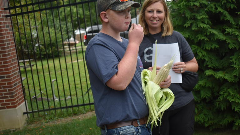 Elisha Fisher watches while her son, Brooks, 11, takes a bite from an ear of Texas Gourdseed at the Central State University Extension Homeschool Adventures program