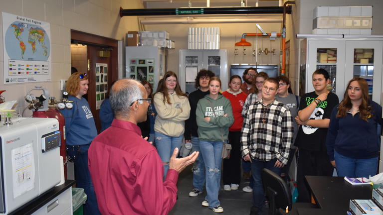 a group of young people listen while a Central State University professor discusses his research