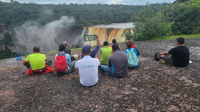 A student group gazes across a waterfall of a rainforest in Guyana.