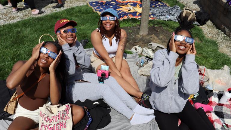 four central state university students smile with eclipse glasses